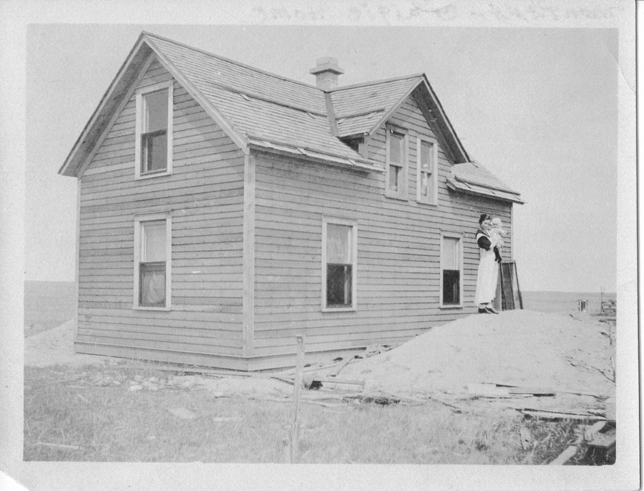 Agnes with Jean on dirt pile next to almost finished home in Montana